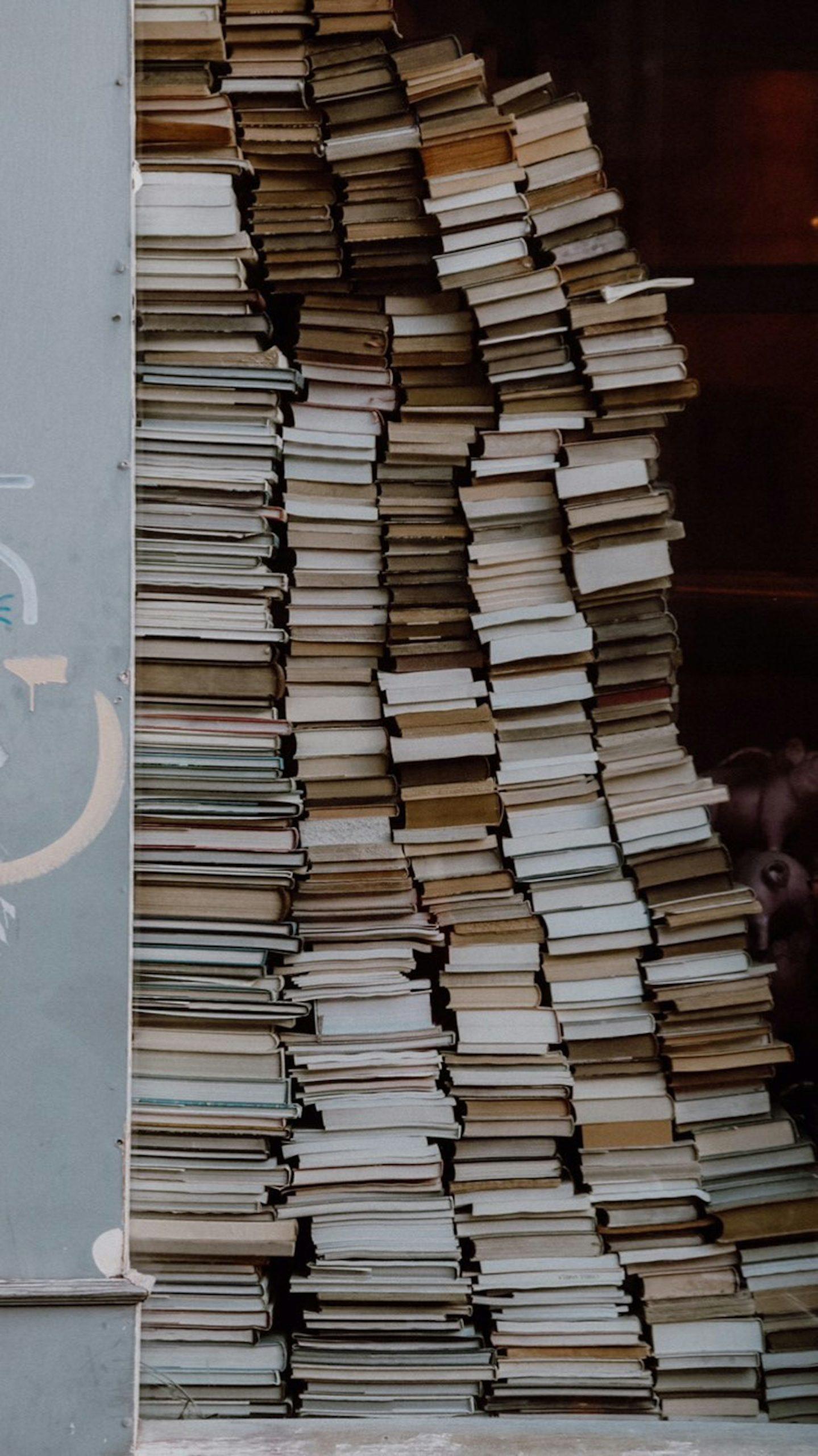 Des livres empilés derrière une vitrine.