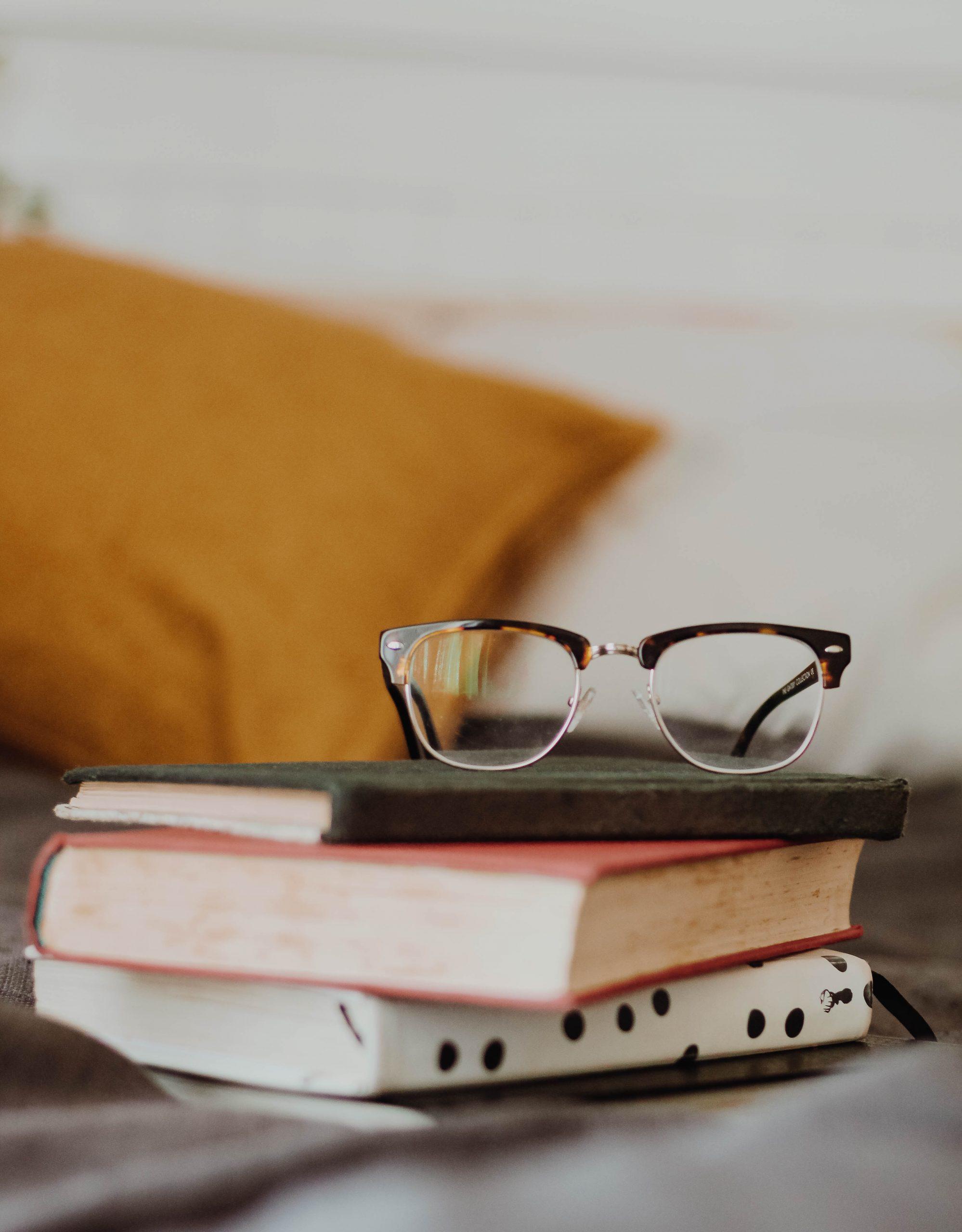 Une pile de livres et une paire de lunettes.