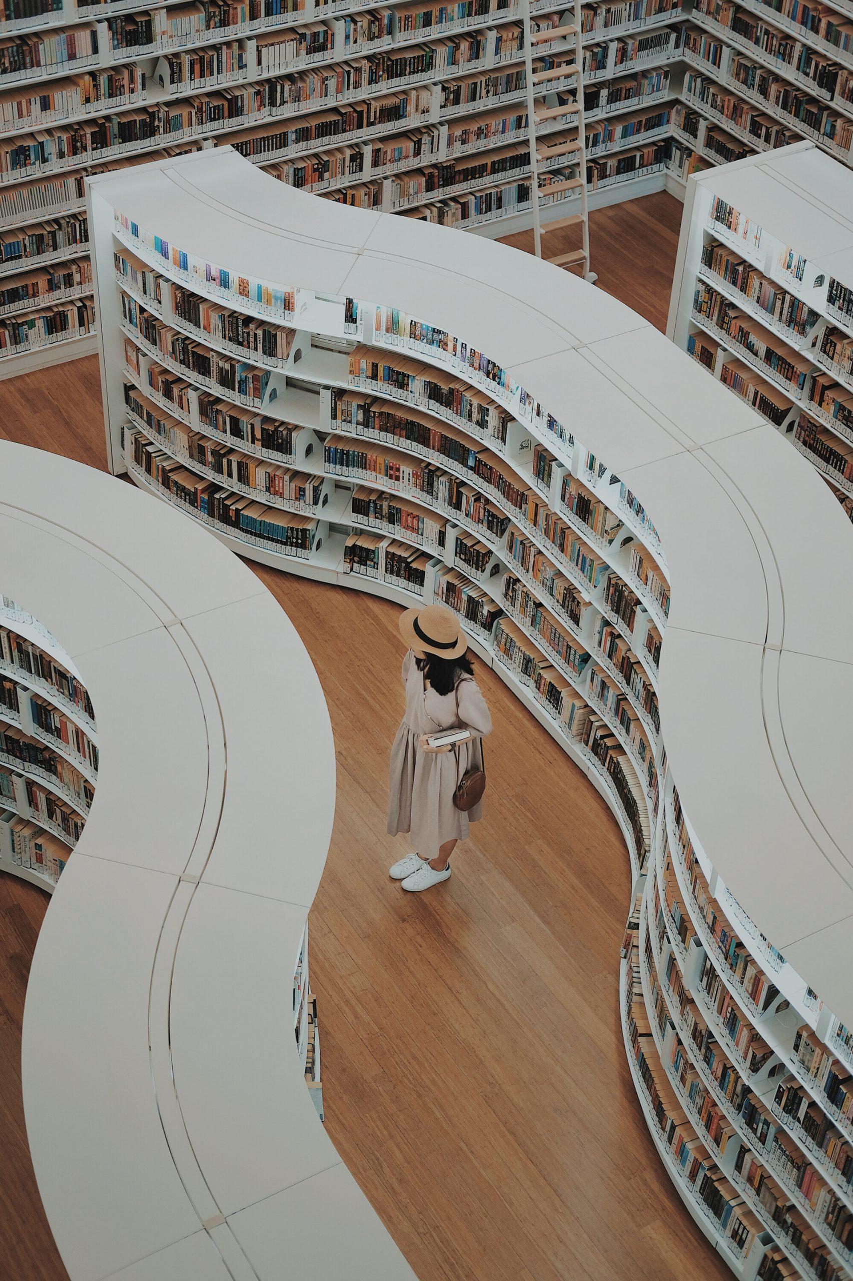 Une fille se balade entre les rayons d'une bibliothèque.