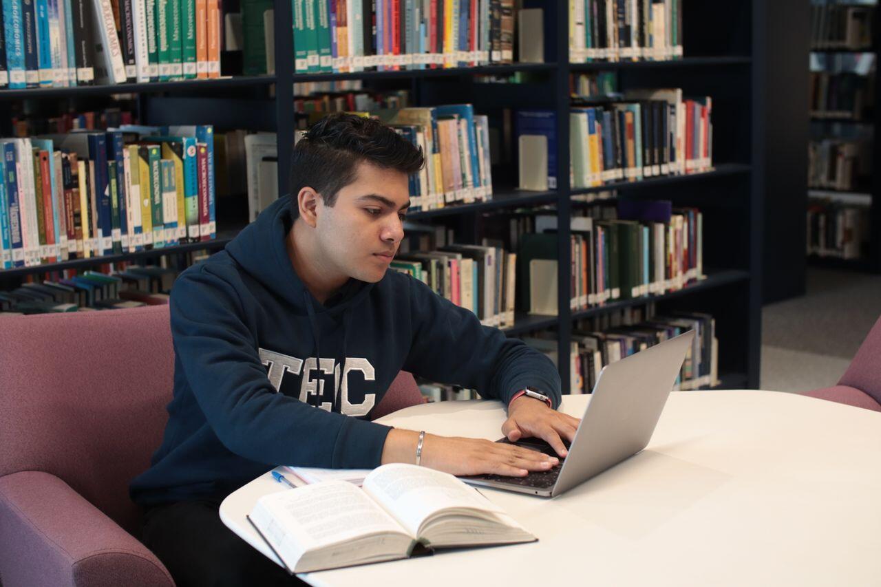 jeune homme avec son ordi etudiant a la bibliotheque