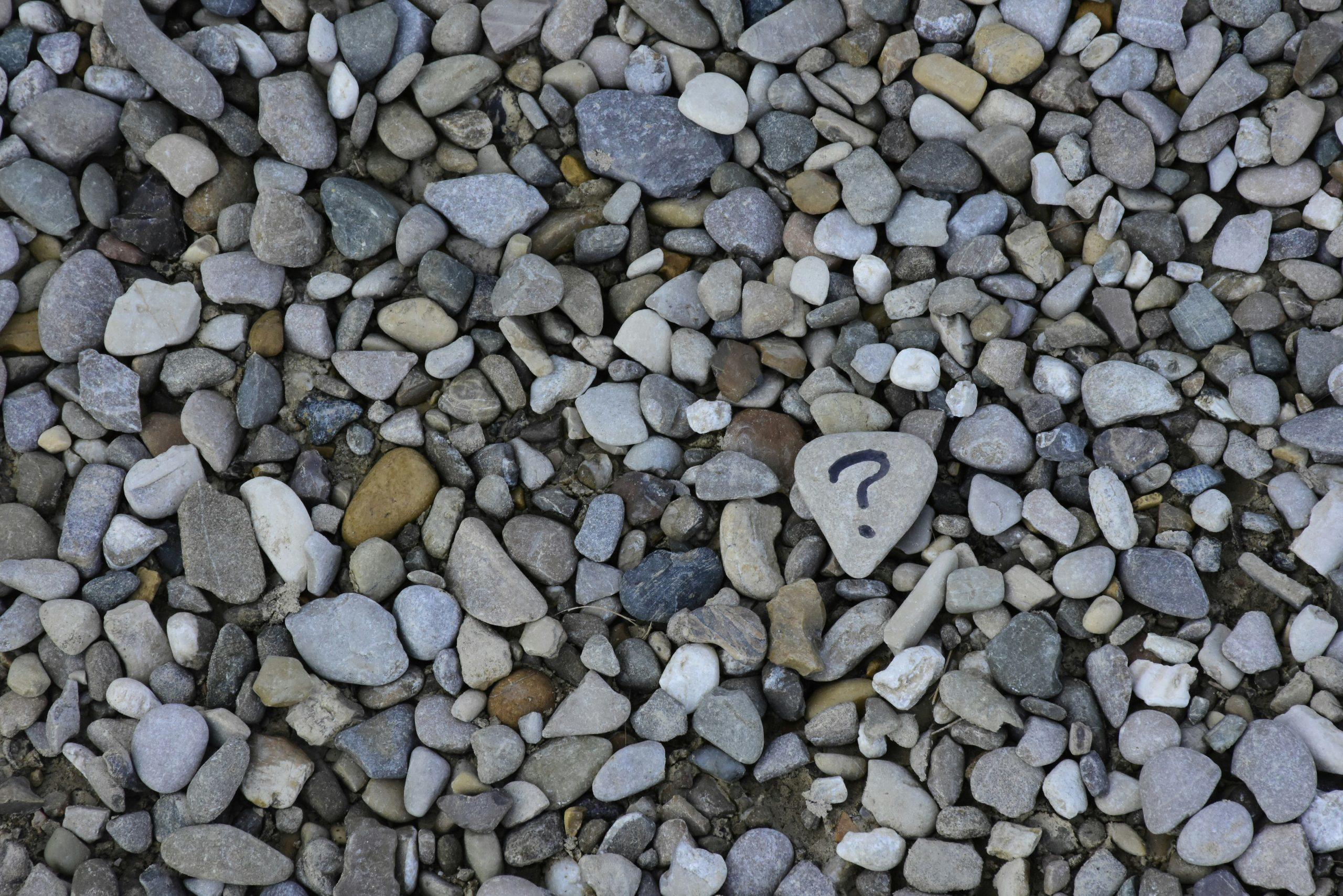 Une plage de galet avec un point d'interrogation sur l'un d'eux.