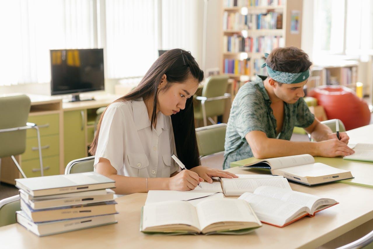 deux ado a une table etudiant avec leurs livres et cahiers serieusement