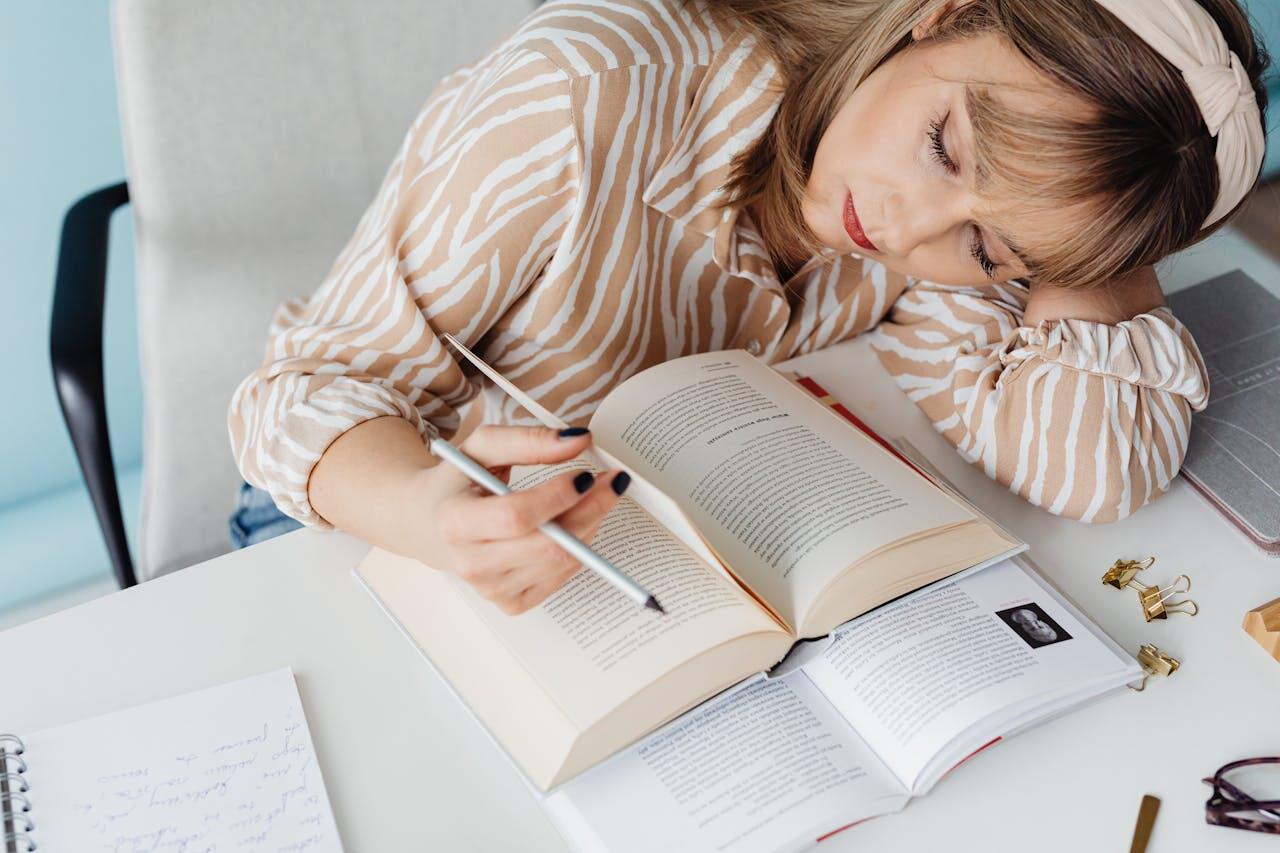 jeune femme manucuree en train de s endormir sur son bureau et ses livres