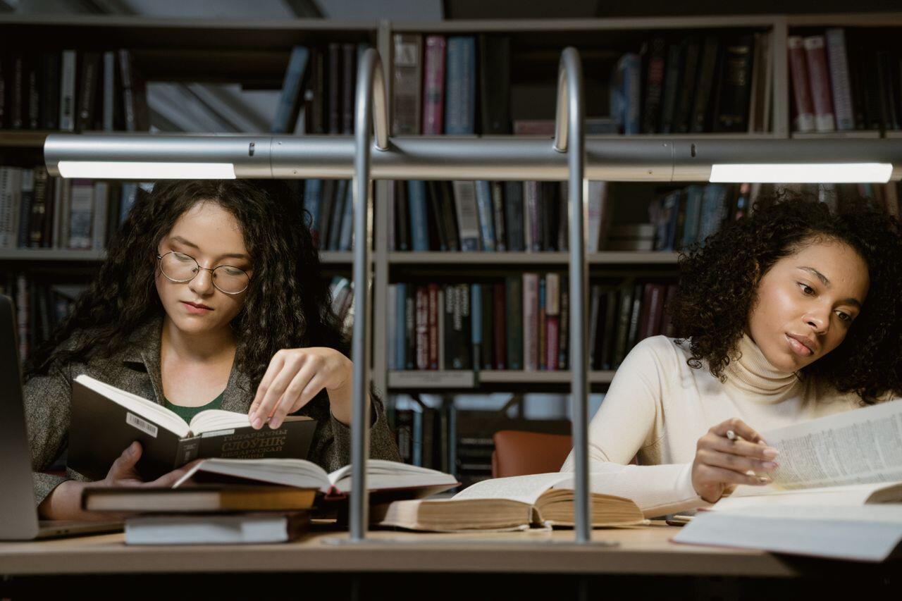 deux jeunes femmes etudiant dans une bibliotheque