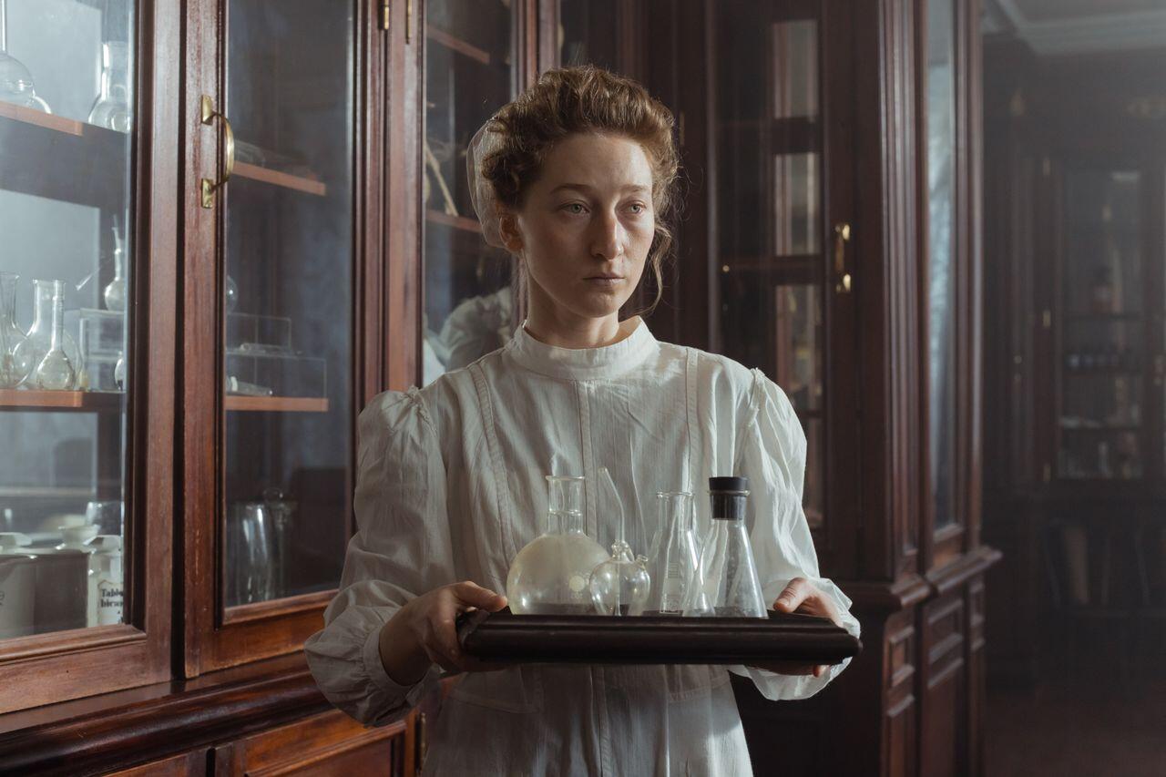 Marie Curie tenant des fioles de chimie dans son labo