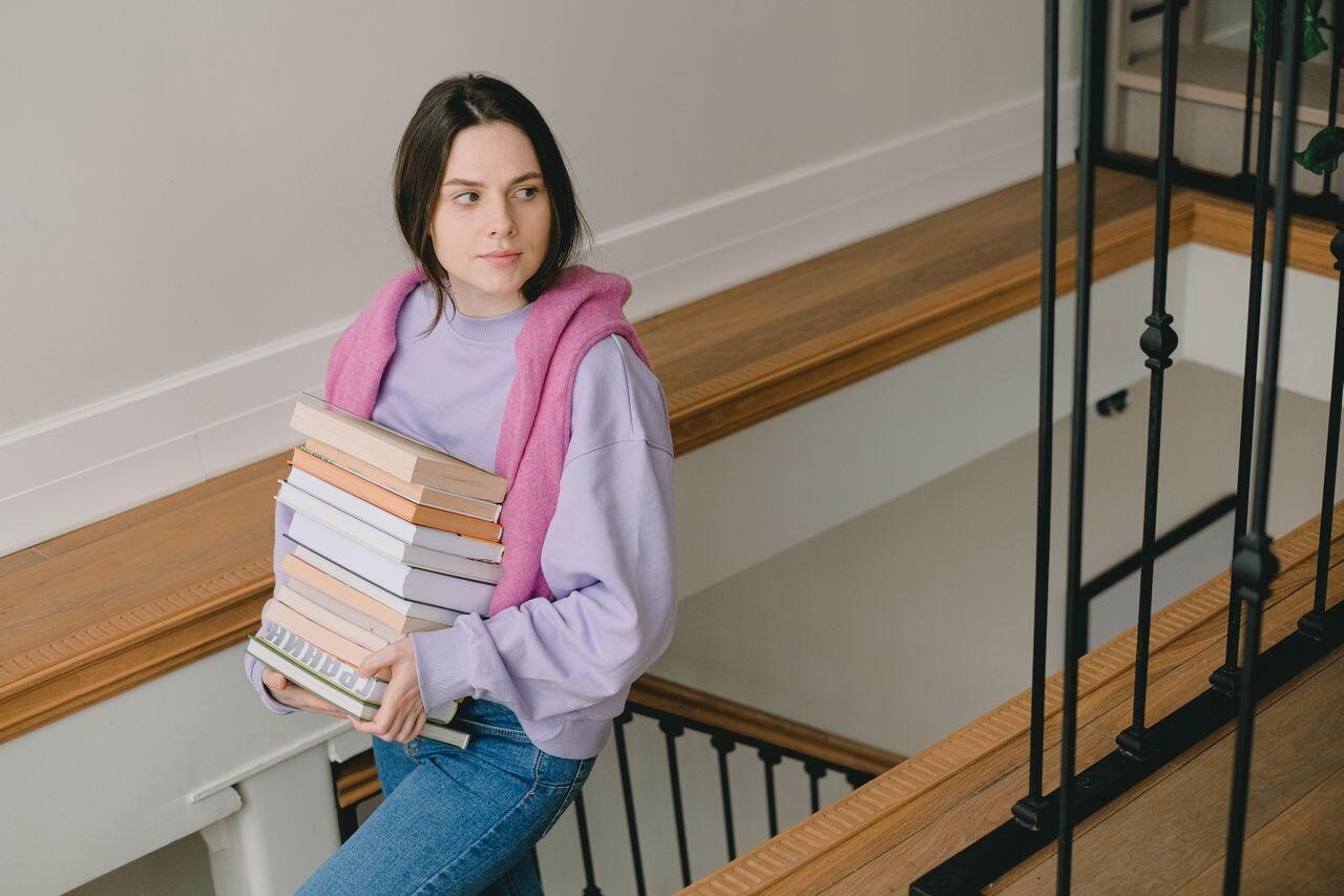 ado en violet et rose portant une pile de livres