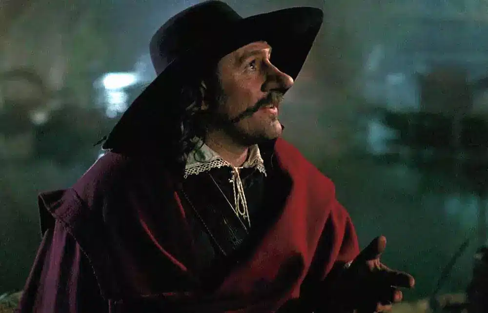 acteur jouant Cyrano de Bergerac en manteau rouge