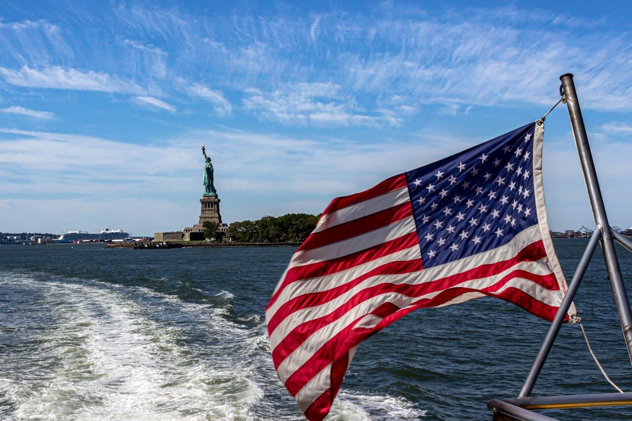 drapeau americain sur la mer et au loin la statue de la liberte