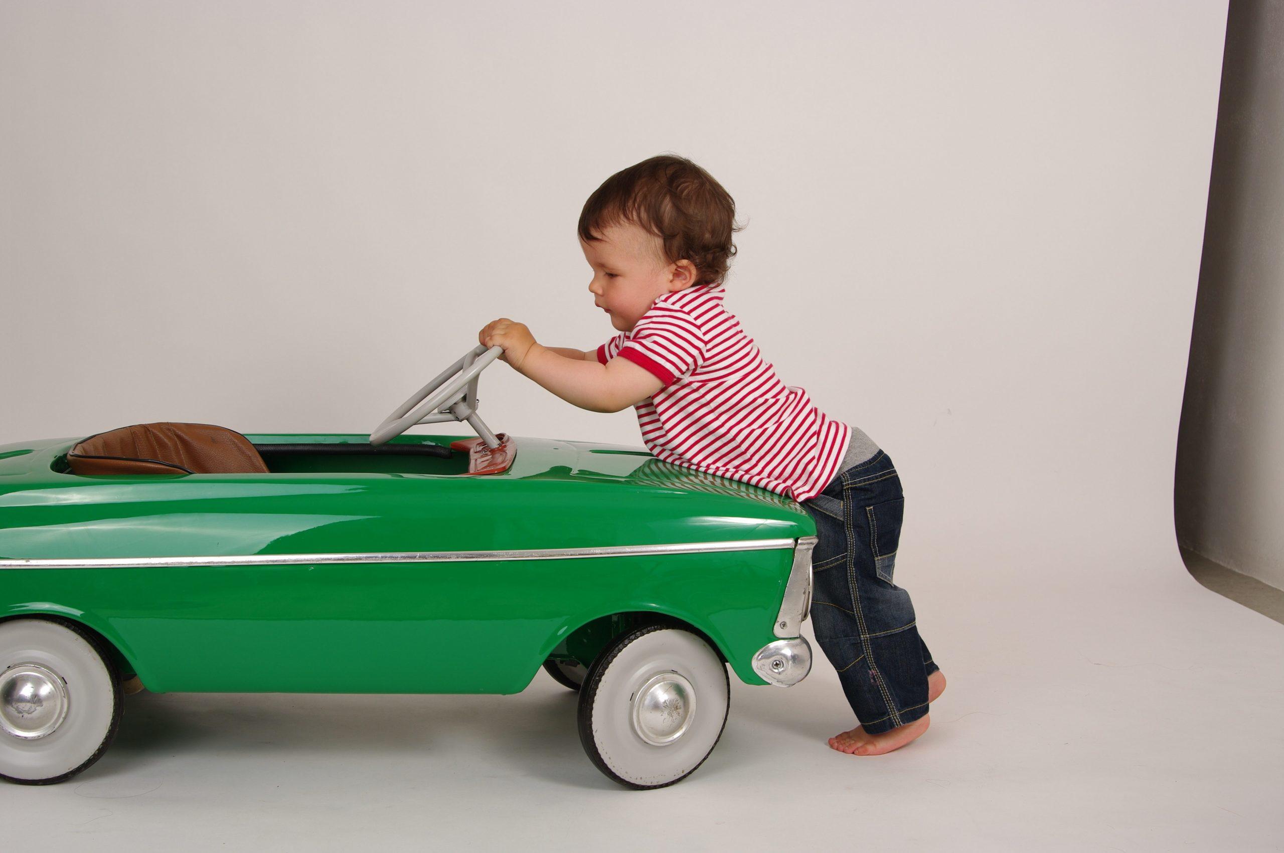 enfant poussant une voiture verte miniature