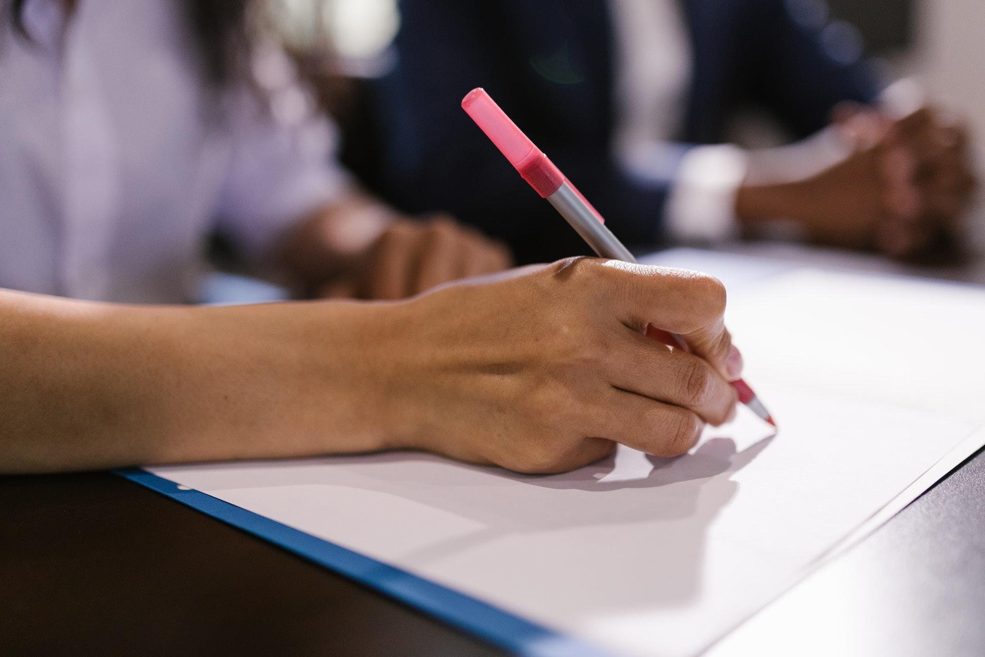 personne en train de rédiger un texte avec un crayon rouge