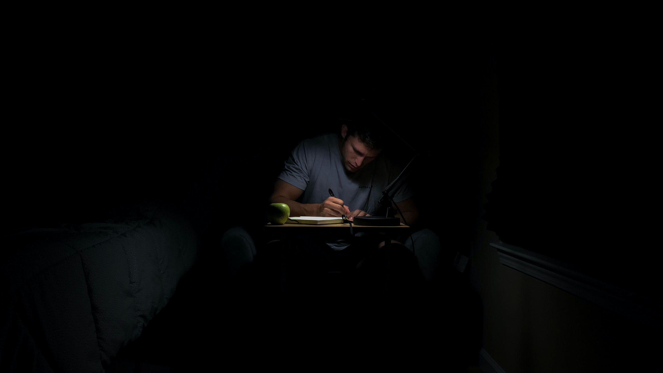 Un homme écrit dans le noir.