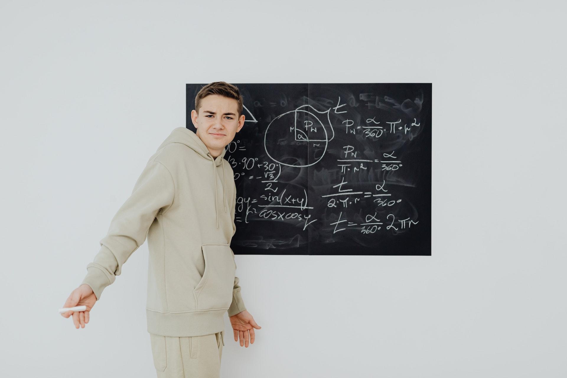 jeune garçon au tableau avec formules mathématiques