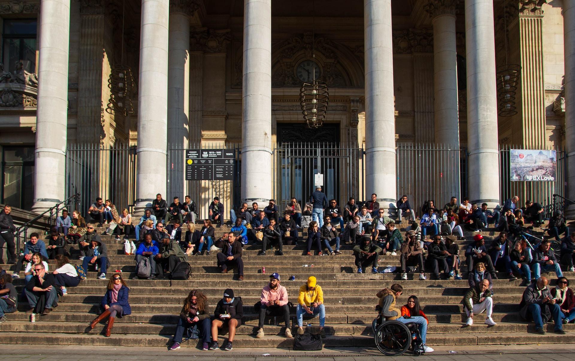 foule de personnes assises sur les marches d'un bâtiment 