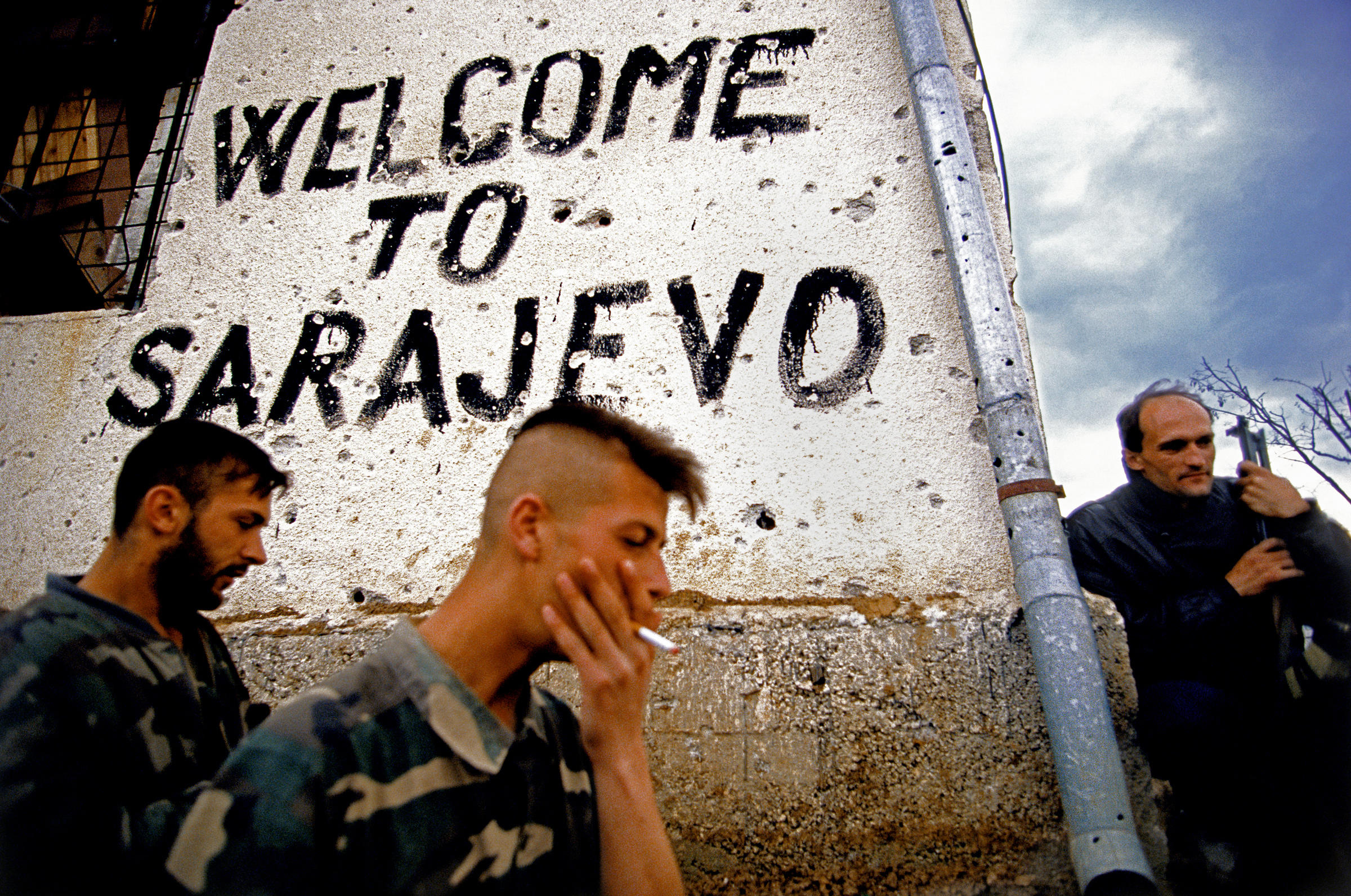 militaires devant un mur avec une inscription "Welcome to Sarajevo"