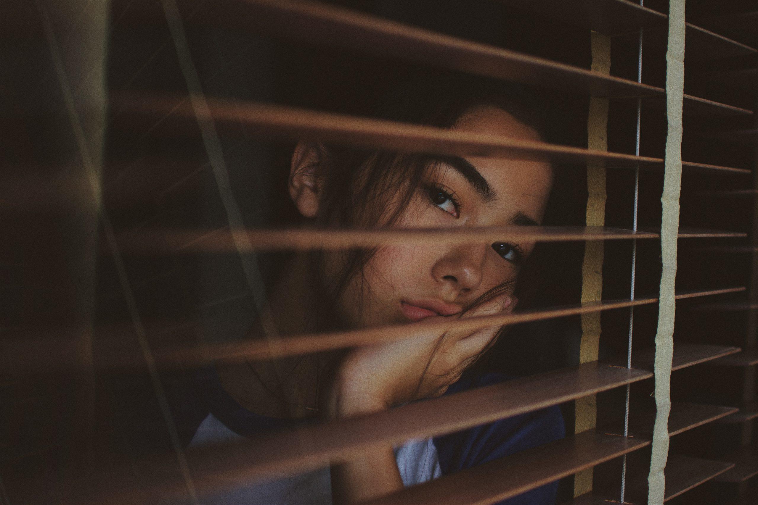 jeune femme regardant à travers une fenêtre et ses volets