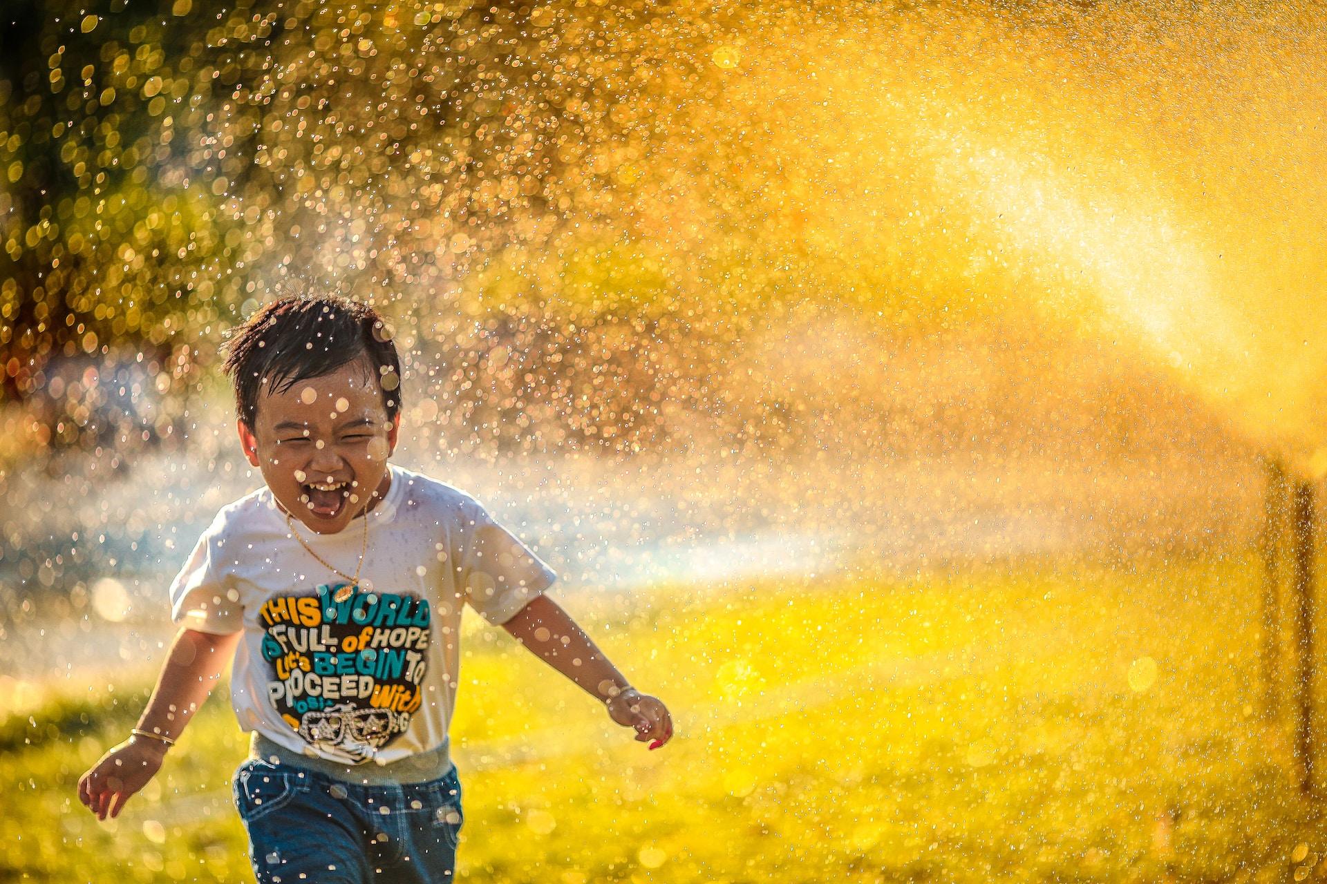 enfant qui court sous un jet d'eau