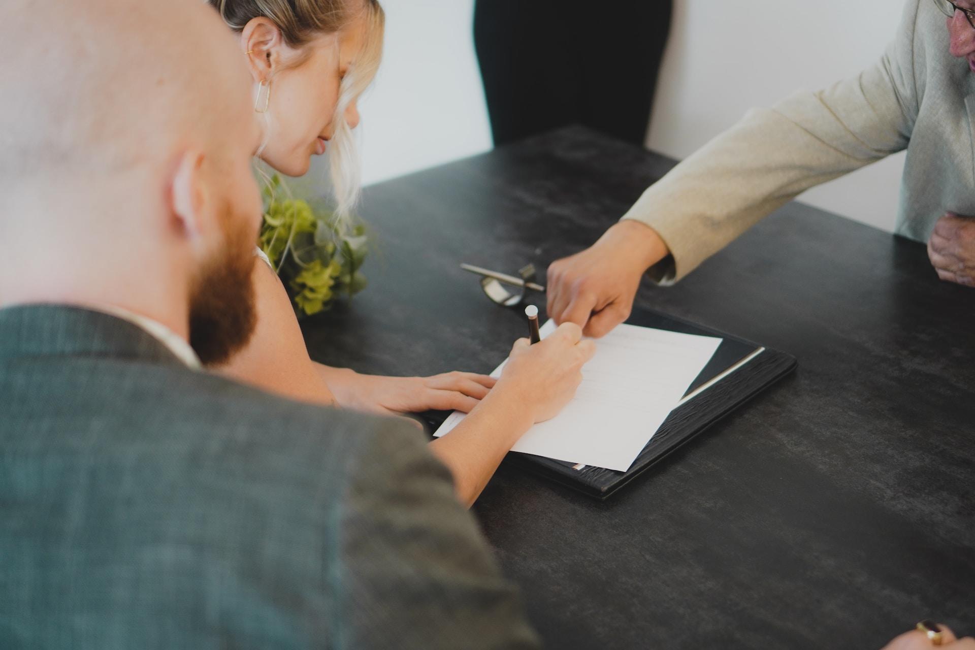 trois personnes en train de signer un contrat 