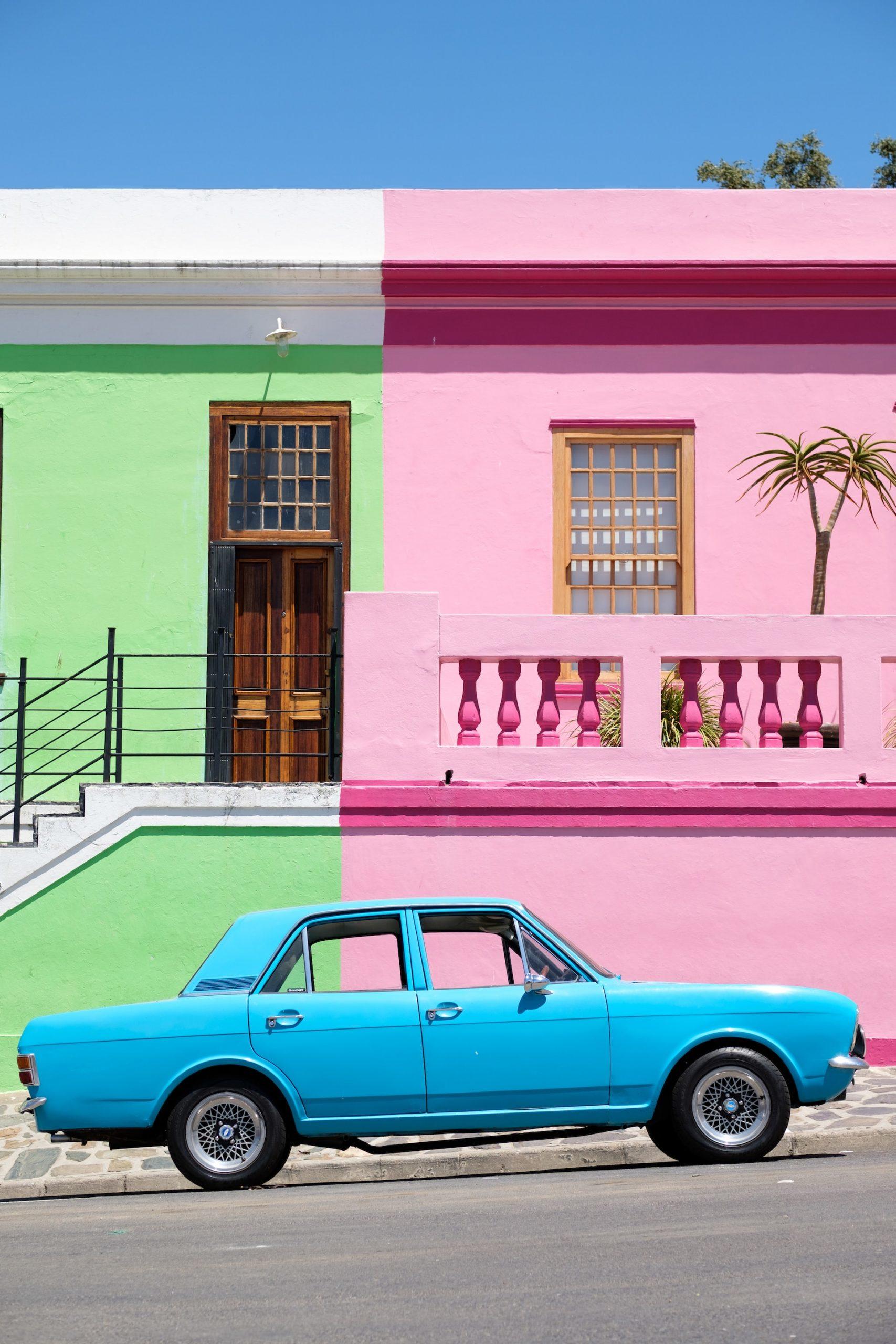 voiture bleue devant maison rose 