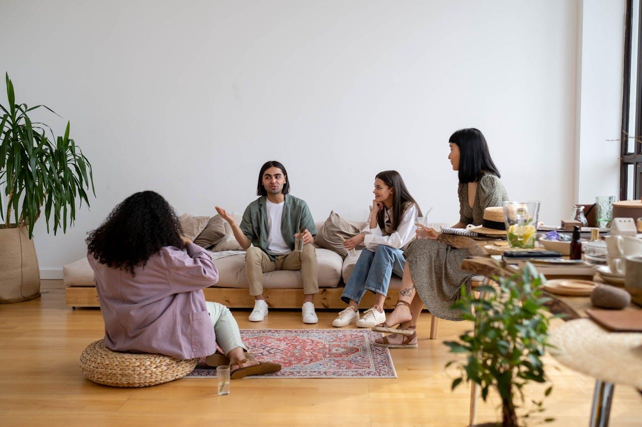 trois jeunes sur un canapé et un quatrieme jeune sur le sol en grande conversation