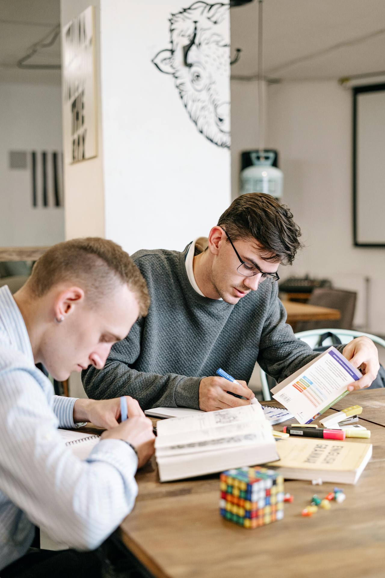 deux jeunes hommes etudiants sur une table avec bouquins ouverts