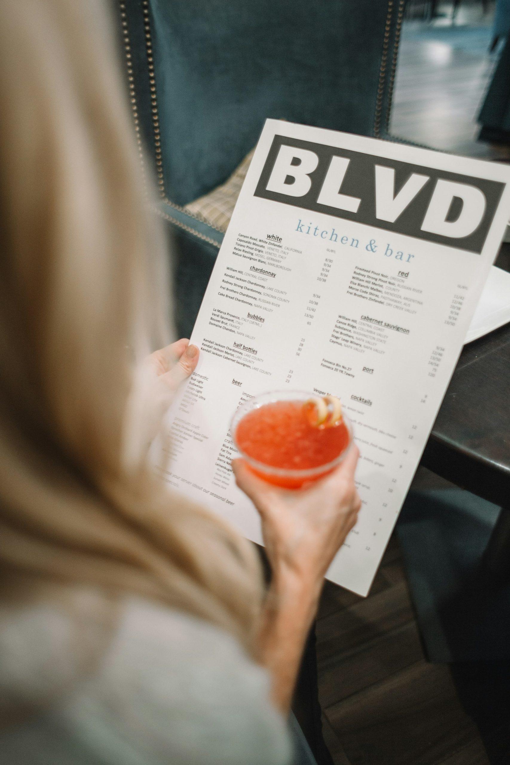 personne tenant une carte de restaurant avec un cocktail