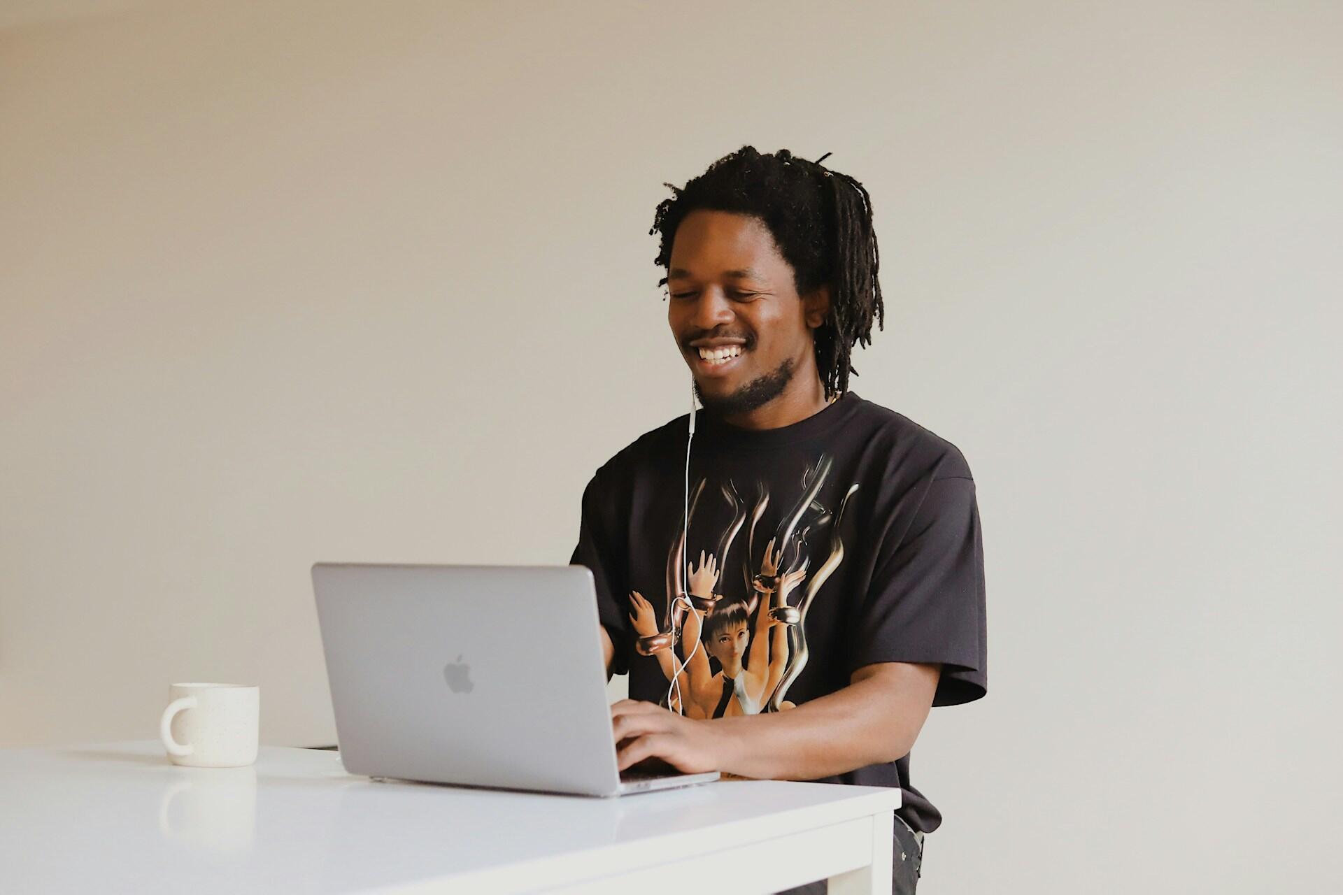 homme a tee shirt et ecouteur sur la table avec son ordi