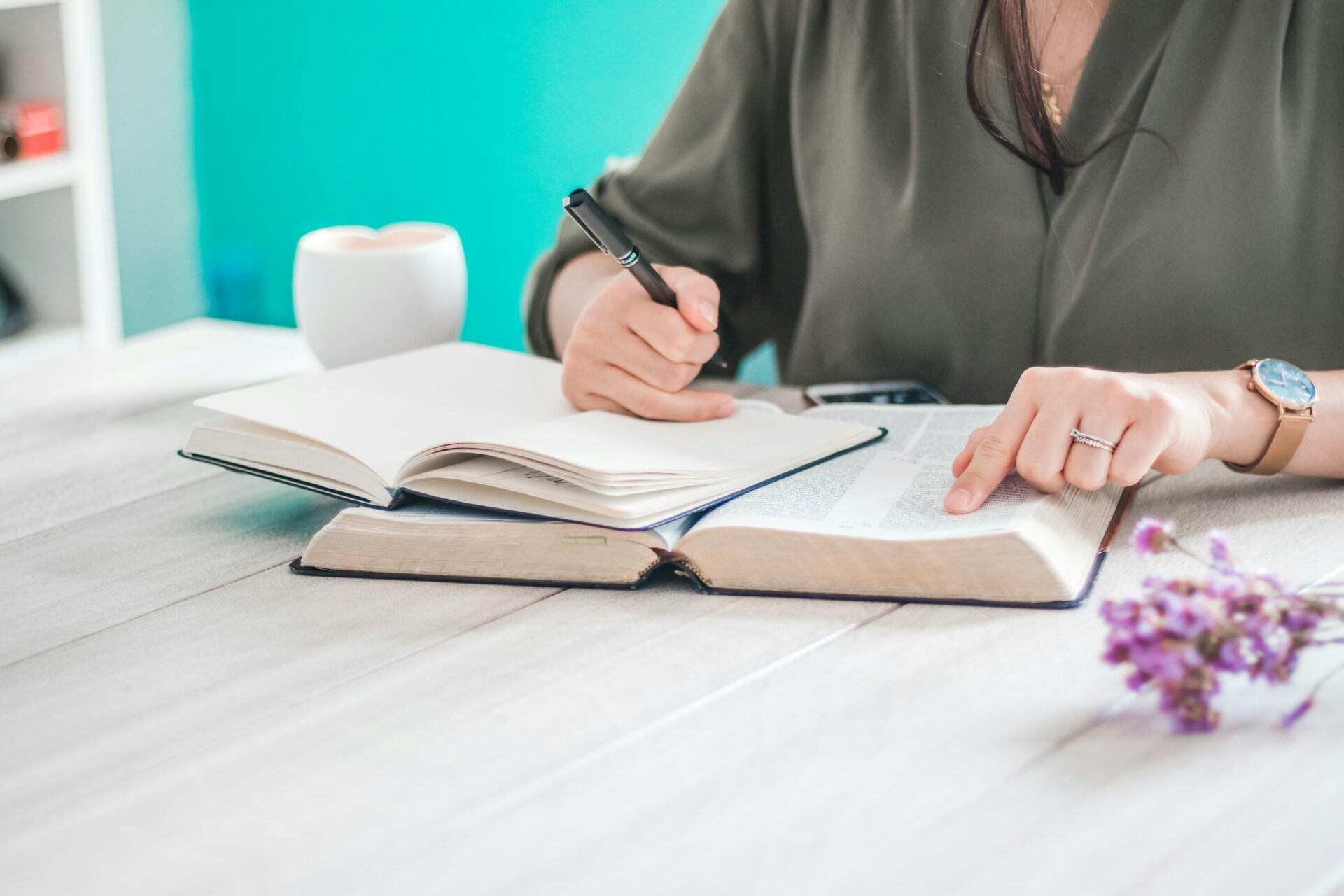 jeune femme au chemisier vers sur sa table avec deux livres et un crayon