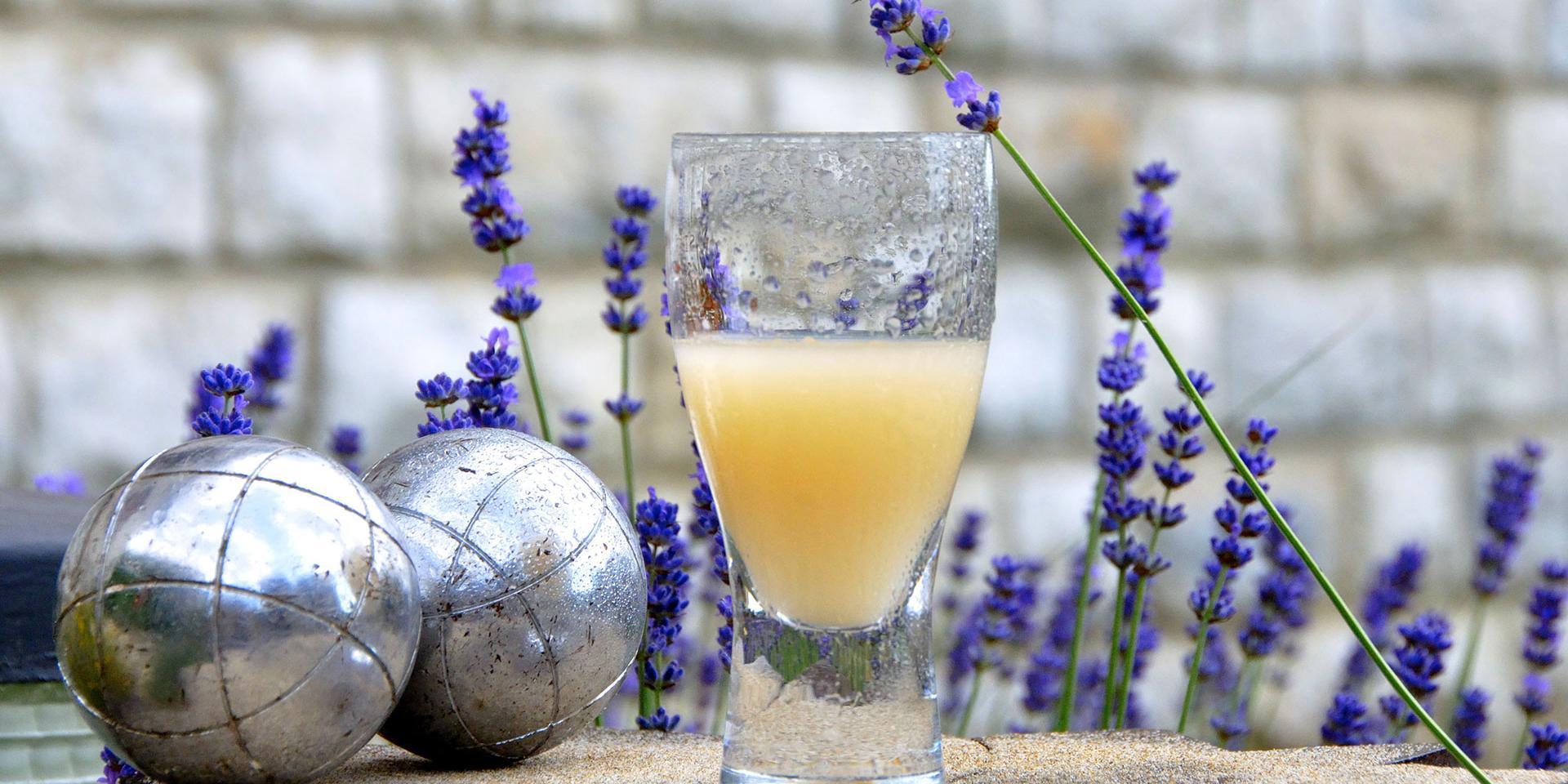 verre de pastis entouré de lavande et de boules de pétanque