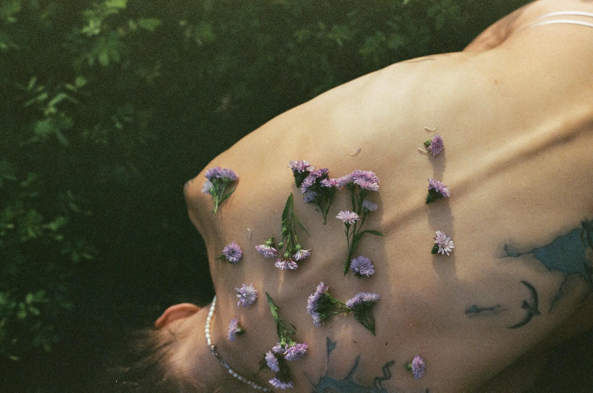 Dos nu d'une femme avec des fleurs mauves