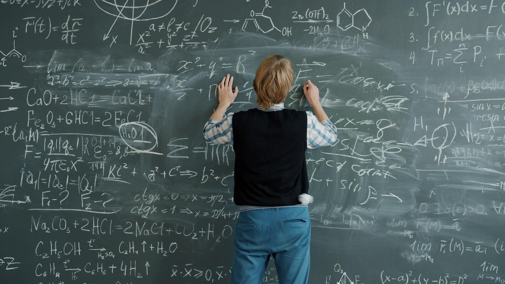 Un élève écrit des expressions mathématiques sur un tableau.