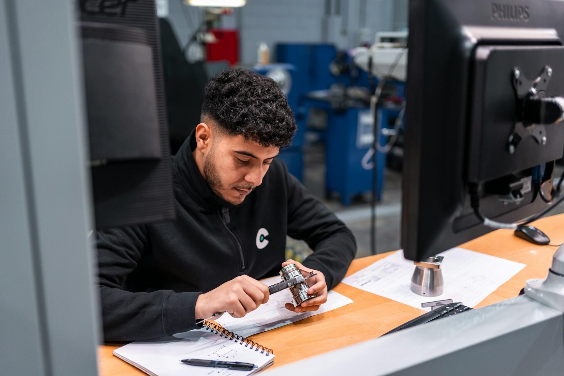 Ingénieur utilisant un pied à coulisse pour mesurer une pièce mécanique