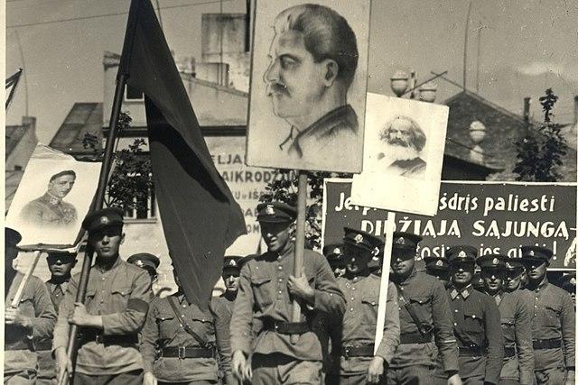 Troops marching with flags showing Stalin and other communist Propaganda