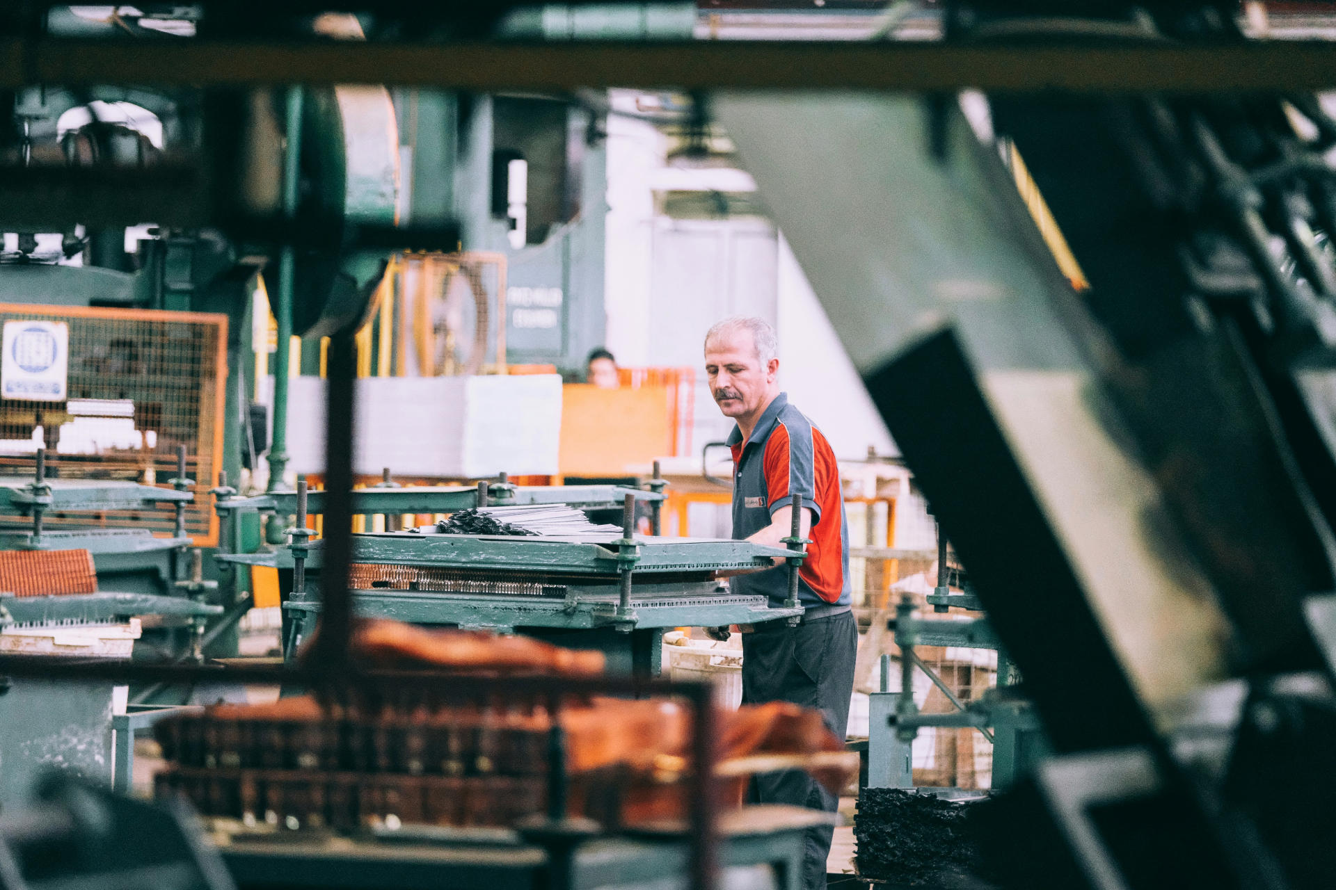 Photograph of an older man working in a workshop or factory setting