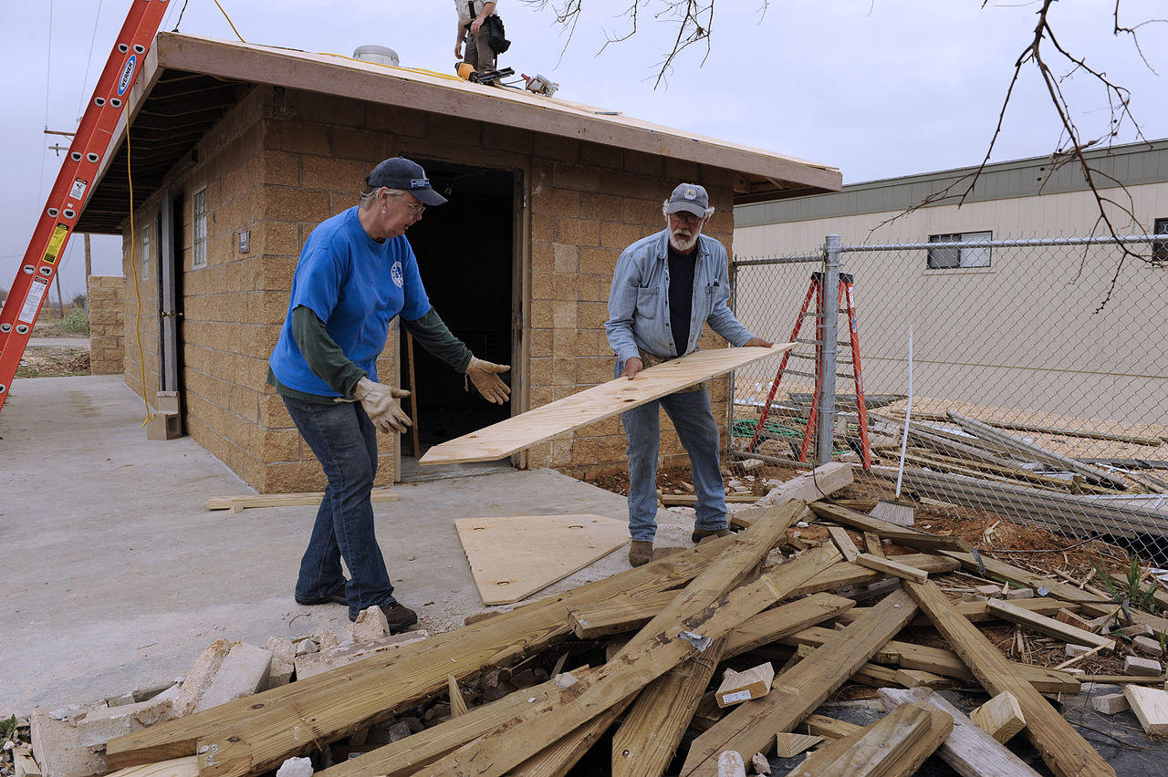 Two men rebuilding a building that has been damged in a hurricane