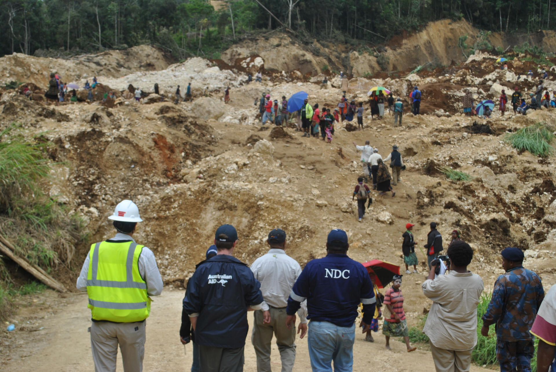 Scene from papa new guinea as onlookers look down on the damage caused by a landslide