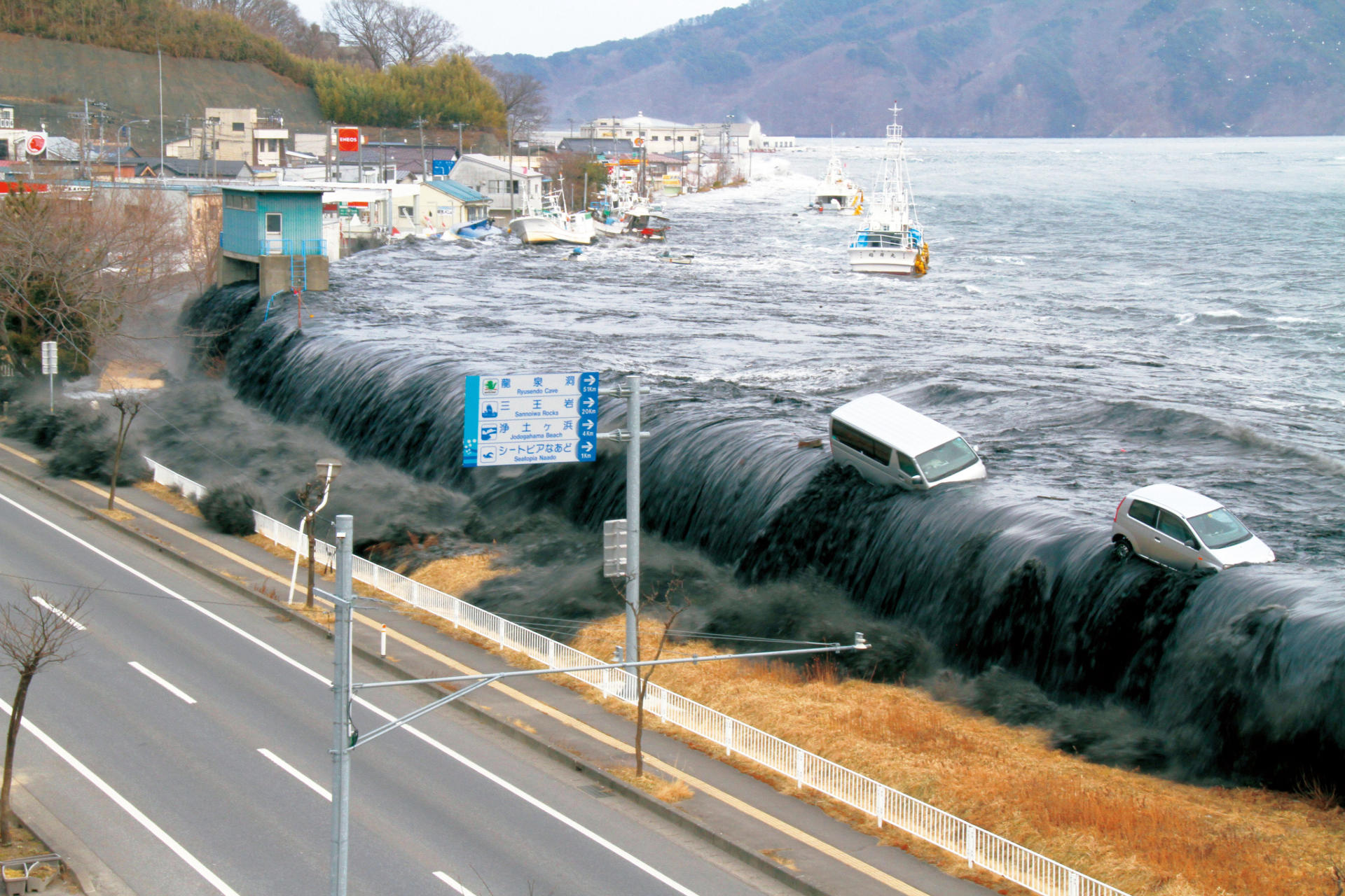 a tsunami carrying cars towards a road in japan