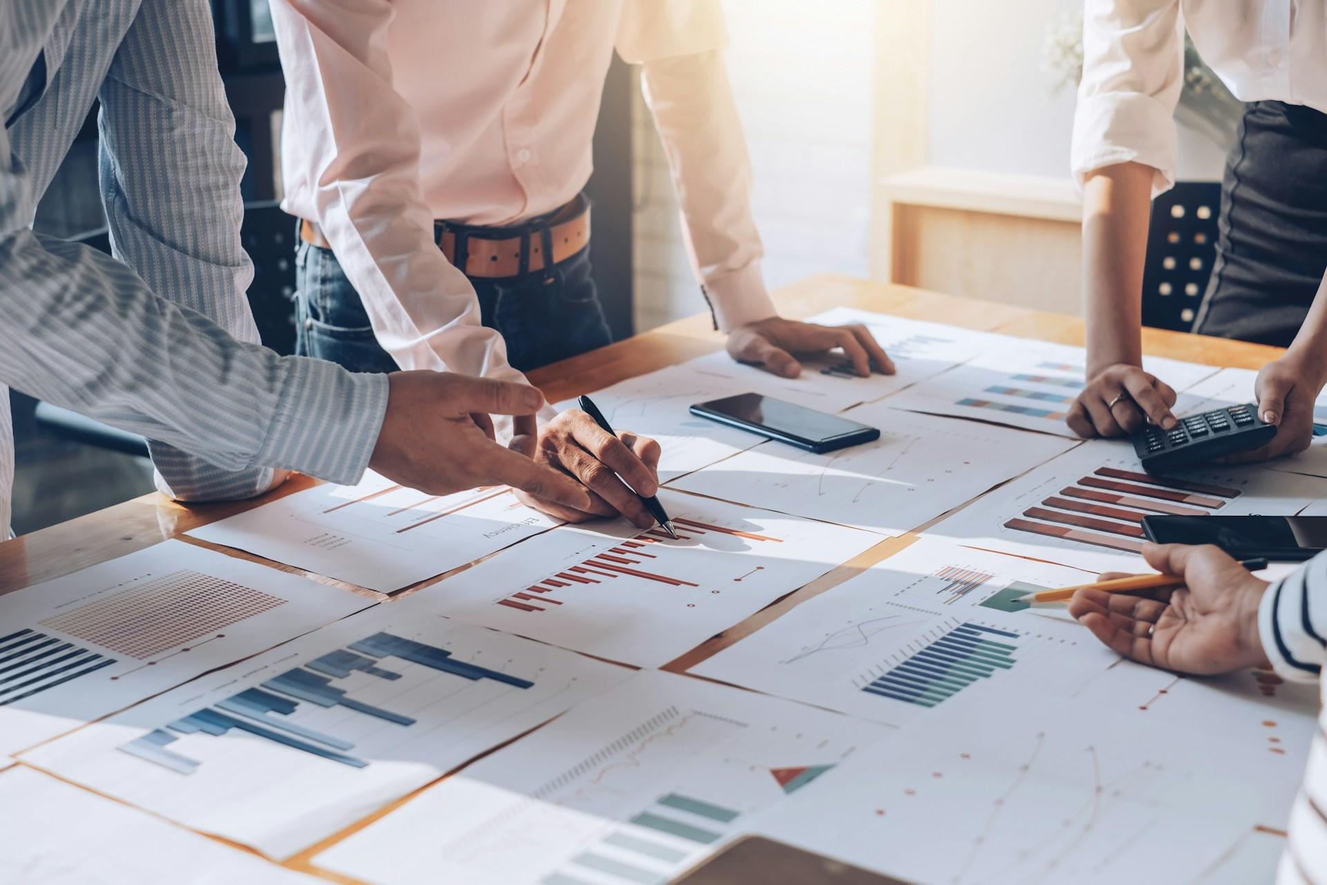 A group of professionals analyzing charts and documents in a business setting.