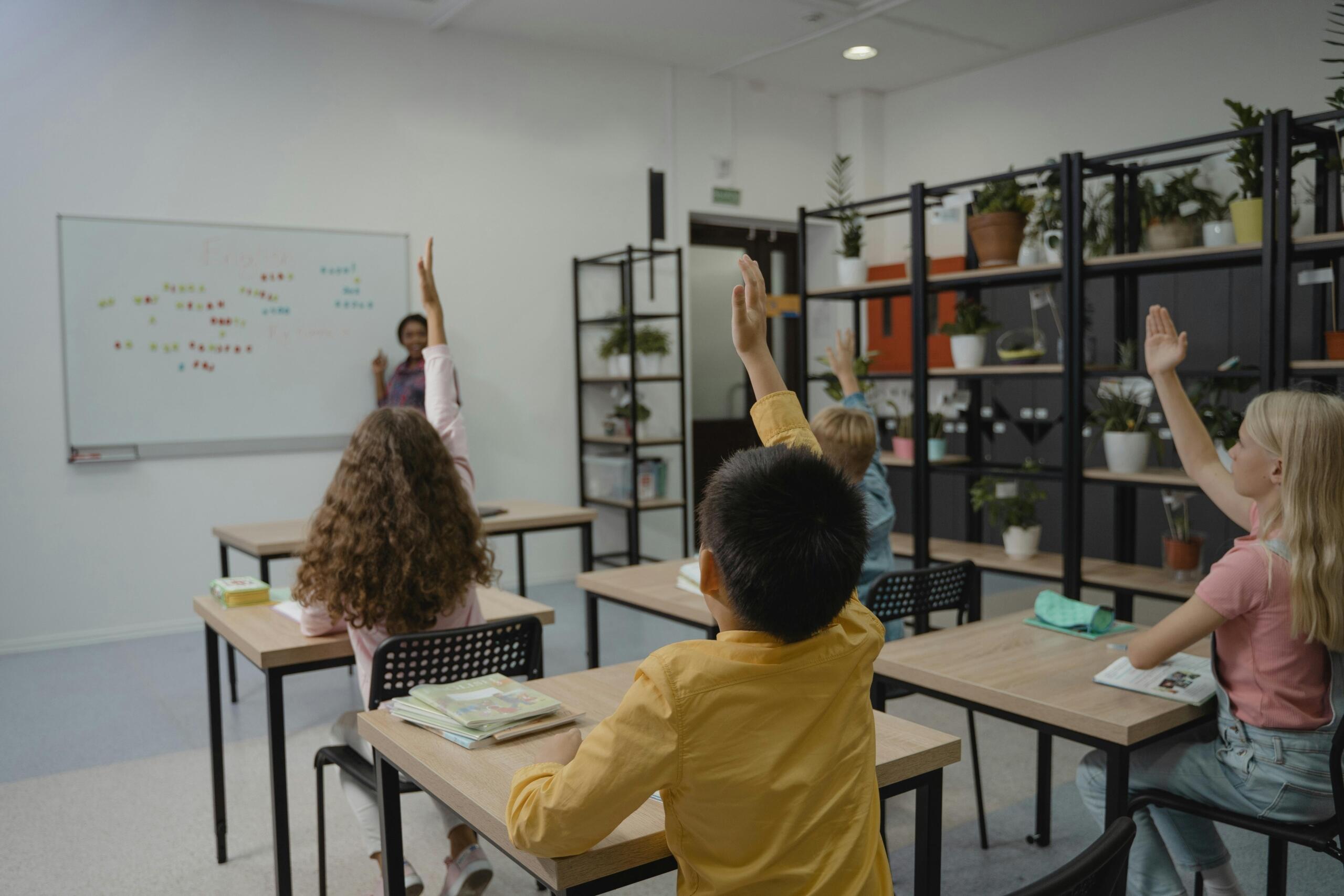 Kids holding hands up in classroom to answer question