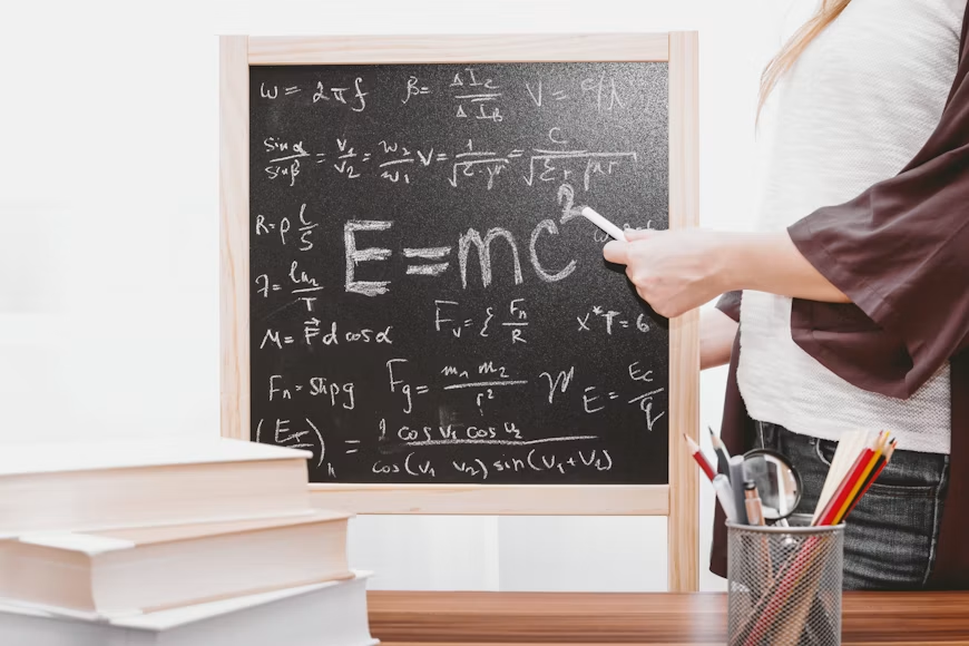 Kultna Ajnštajnova formula teorije relativnosti ispisana belom kredom na tamnoj školskoj tabli, koja simbolizuje revolucionarna otkrića u fizici i duboku povezanost matematike, nauke i našeg razumevanja univerzuma.