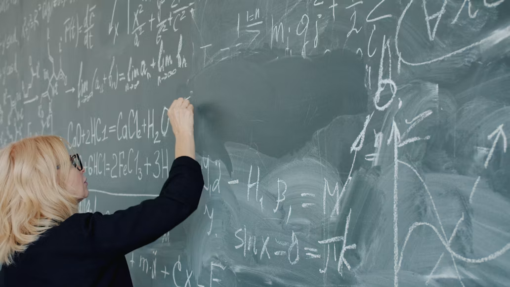 Ozbiljna i posvećena nastavnica prirodnih nauka koja pažljivo ispisuje formule na školskoj tabli tokom predavanja, predstavljajući savremeno obrazovanje, stručnost i strast prema prenošenju znanja.