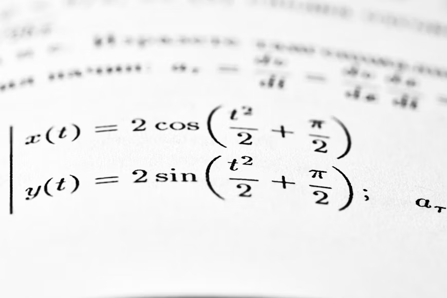 Detaljan kadar štampane stranice iz školskog udžbenika prirodnih nauka, na kojoj su jasno vidljive matematičke formule, jednačine i dijagrami. Fokus je na teksturi papira i sitnim detaljima štampe, što dočarava atmosferu učenja i izučavanja egzaktšnih disciplina.