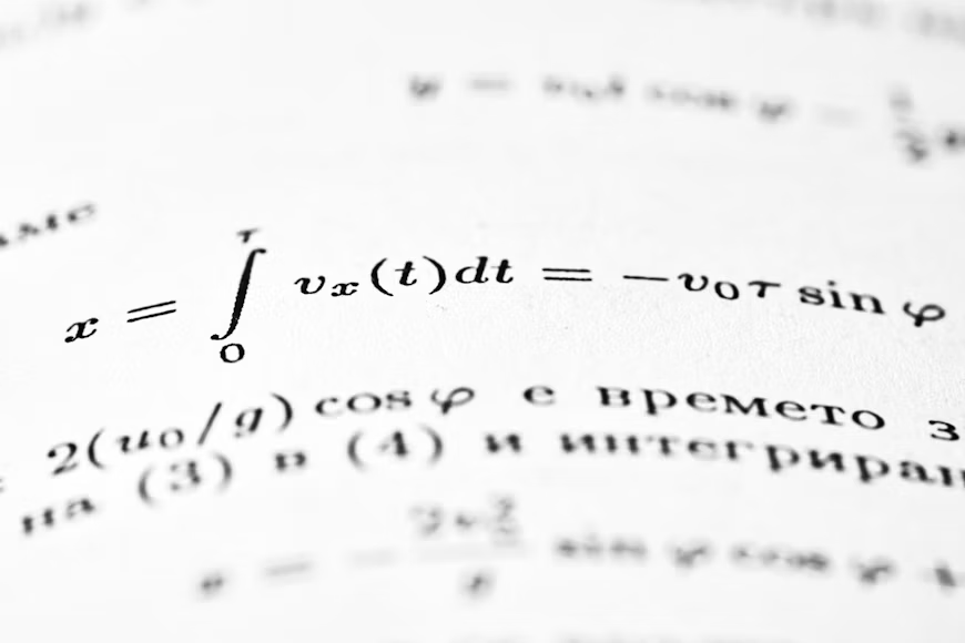 Krupni kadar bele stranice iz školskog udžbenika na kojoj su precizno ispisane matematičke formule. Čist prikaz i oštri detalji naglašavaju jasnoću teksta, stvarajući atmosferu fokusiranog učenja i savladavanja gradiva.