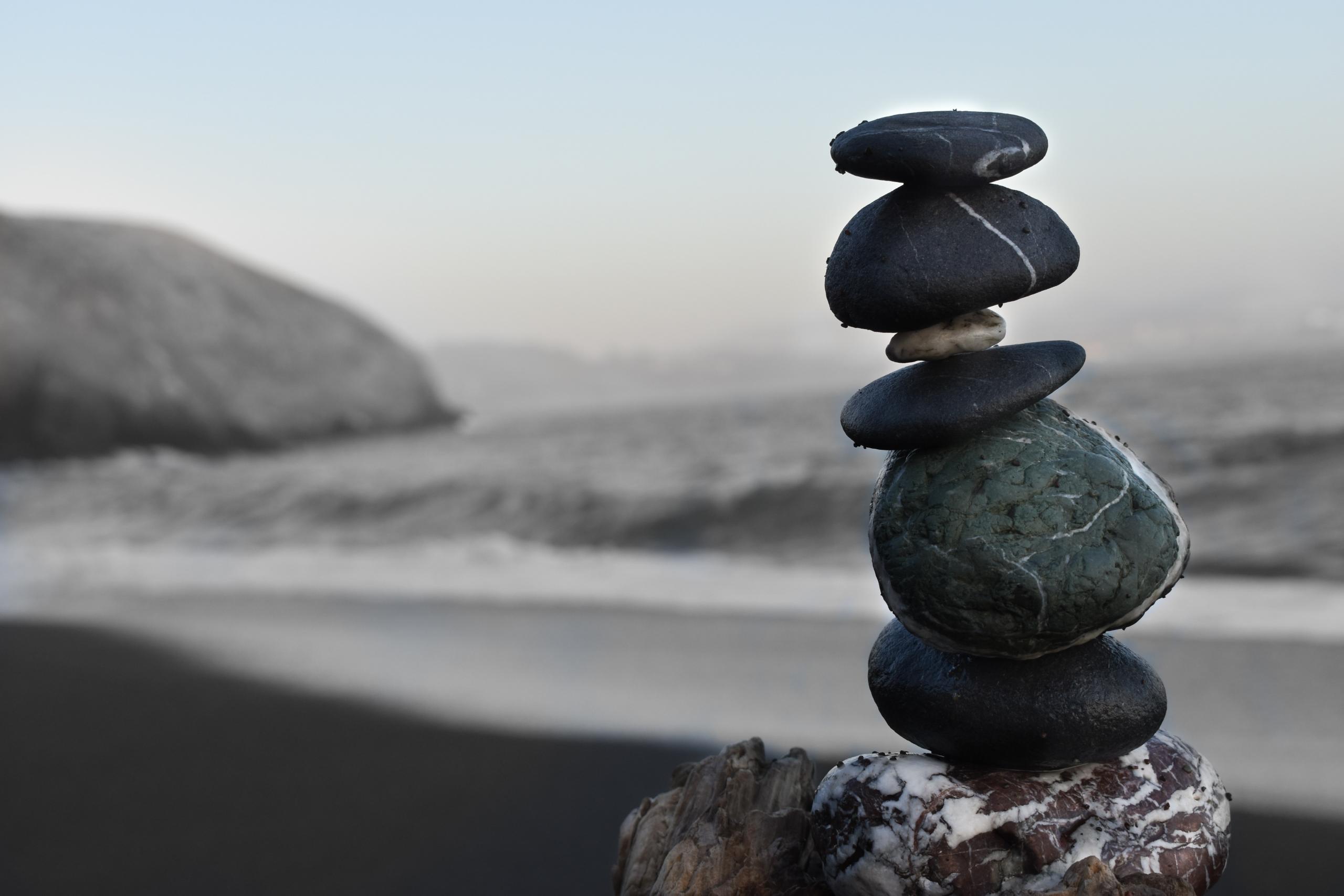 En staplad stenhög vid havet som symboliserar inre meditativ balans.
