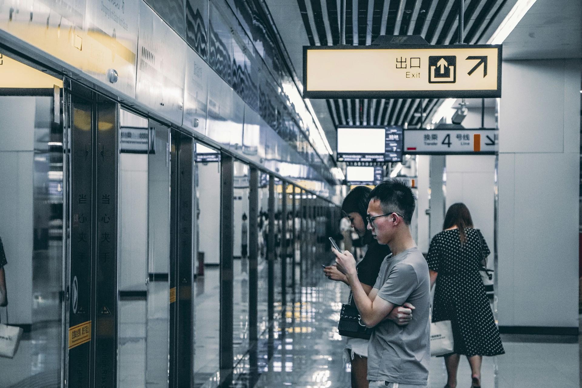 Personer som tittar i telefonen medan de väntar på tunnelbanan.