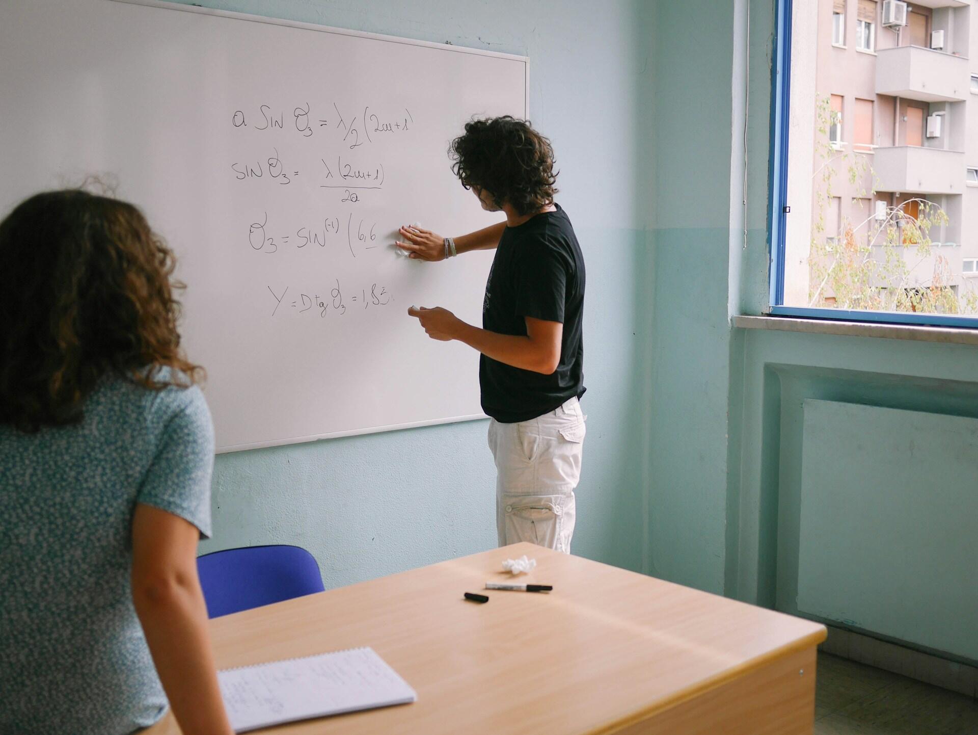 Lärare som räknar matte på whiteboard-tavla.