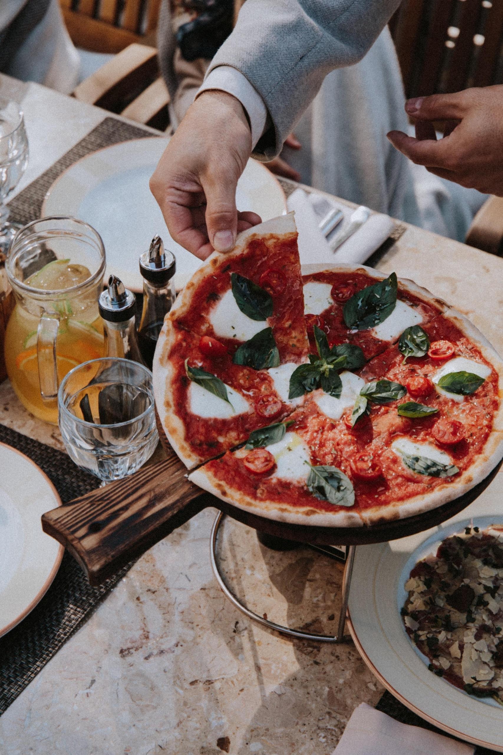 person på restaurang tar en pizzaslice