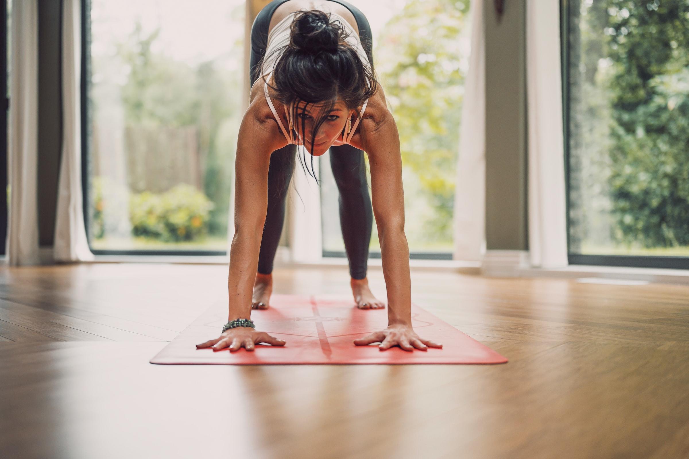 kvinna som står på en röd matta i en yogaposition