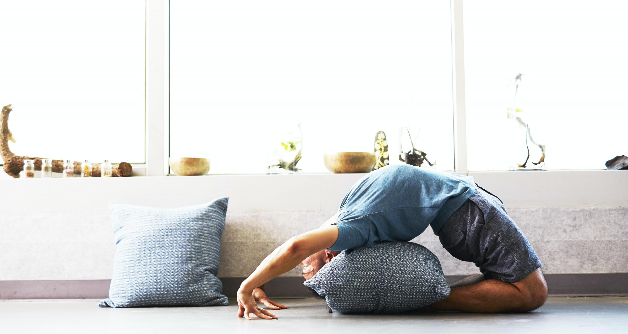 Kvinna som ligger i en yogaposition med en kudde som stöd för ryggen