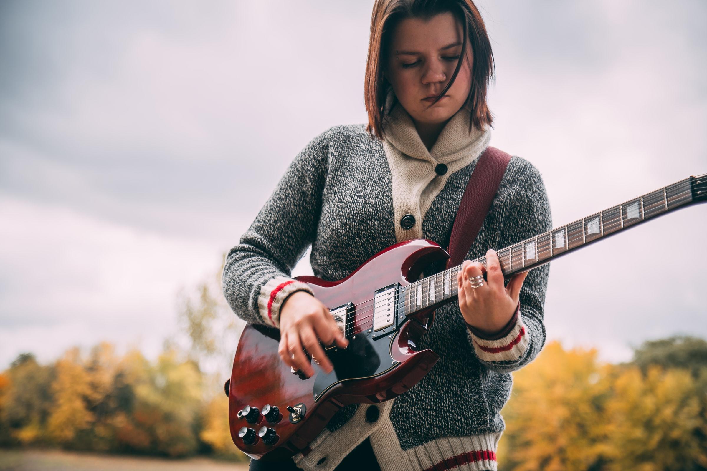ung flicka övar på elgitarr utomhus