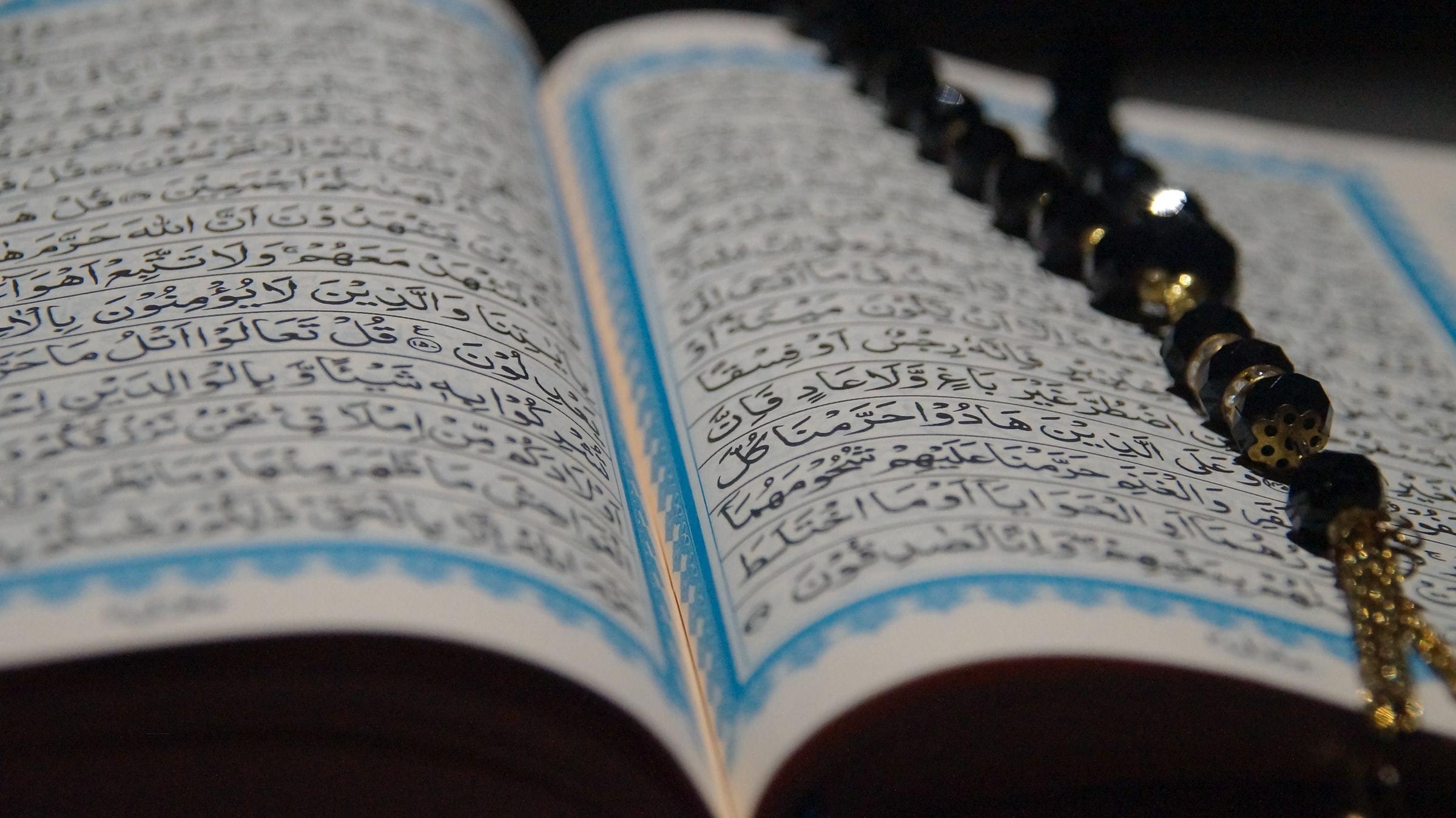 uppslagen bok med arabisk text och ett pärlband
